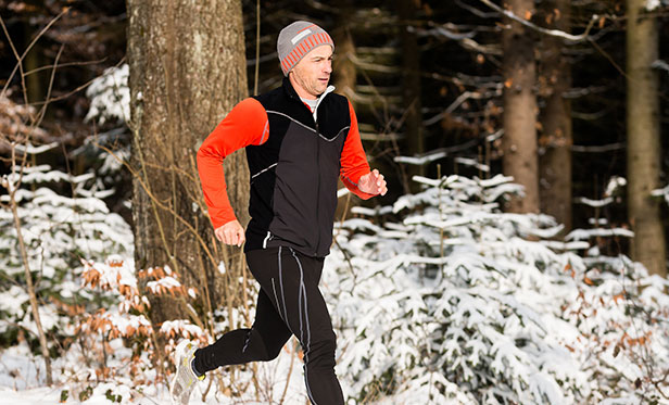 A runner training next to a forest covered in snow